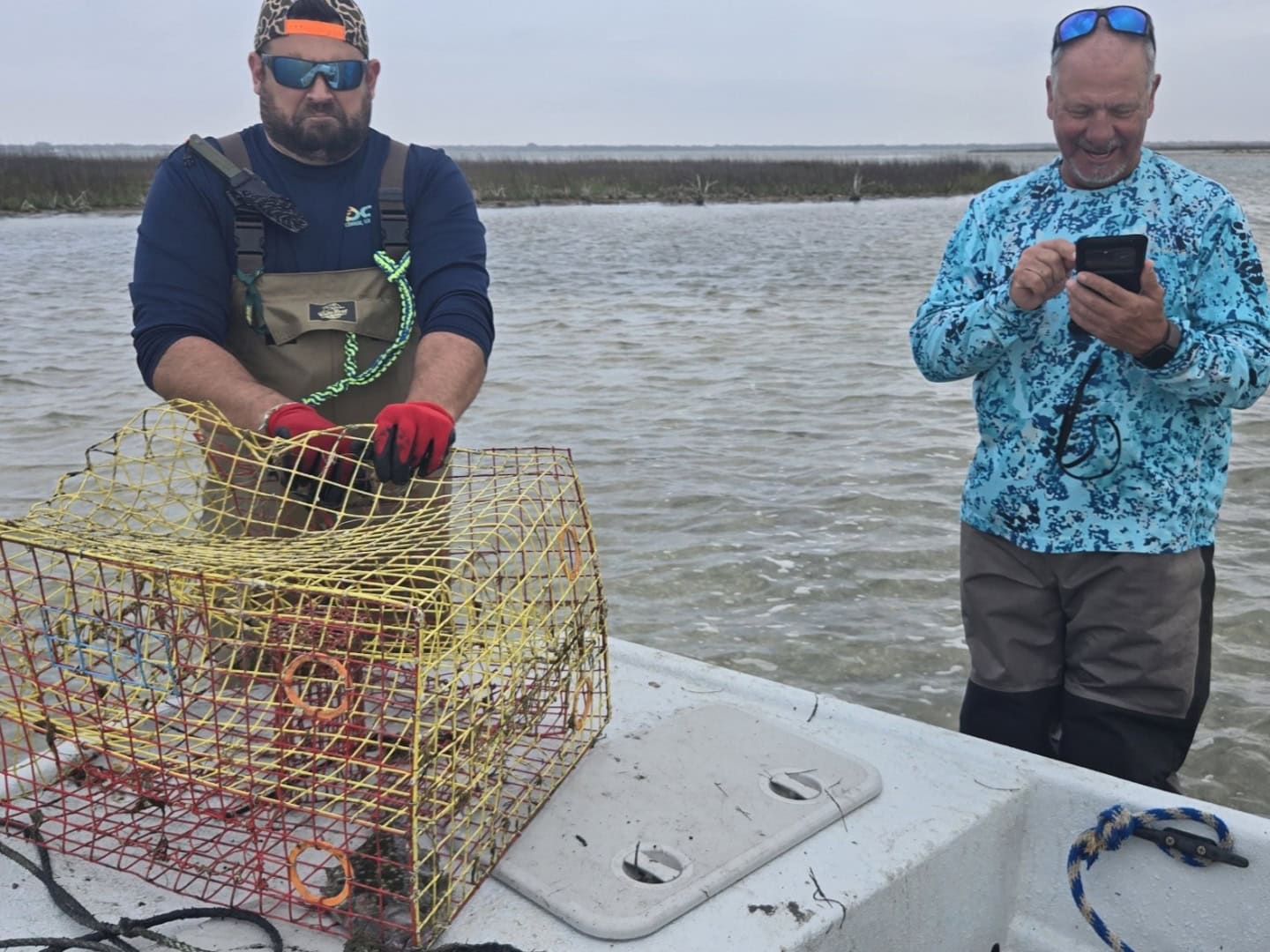 Two volunteers removing and documenting an abandoned crab trap